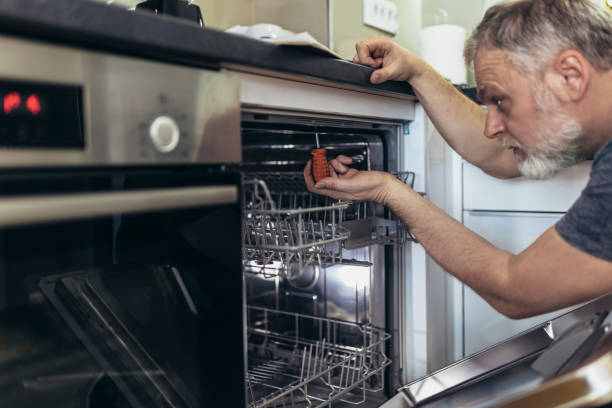 A man is working on fixing a dishwasher in a kitchen setting, demonstrating installation skills.