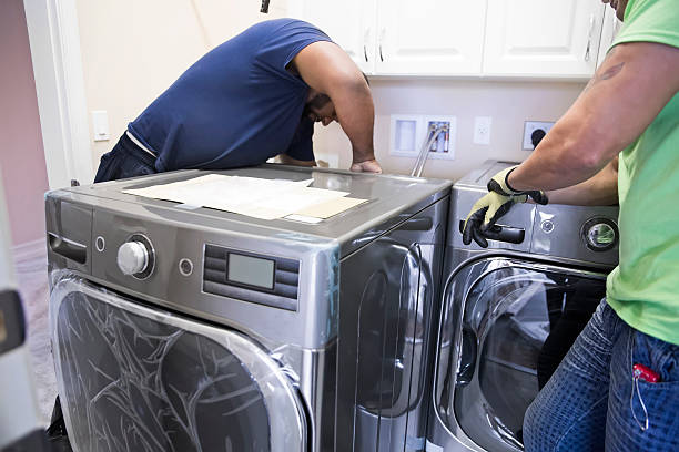 Two men installing a washing machine in a launry, focused on the setup process for washer and dryer installation.