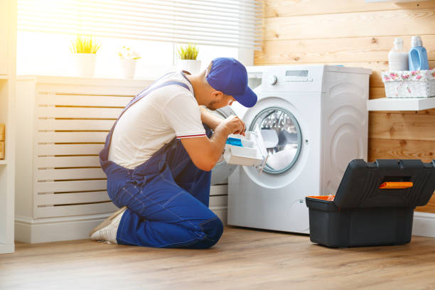 Two men collaborating on the installation of a washing machine in a kitchen, demonstrating washer and dryer installation expertise.