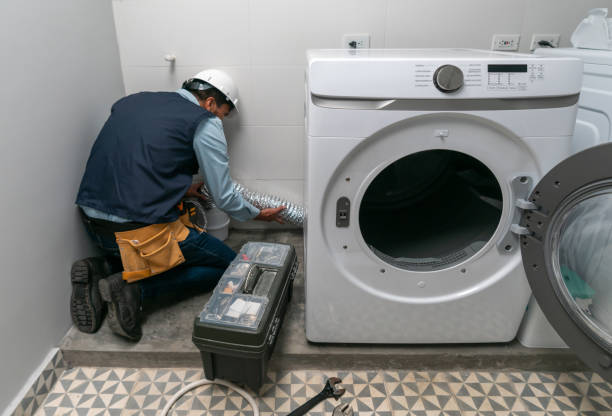 Two technicians working together to install a washing machine in a kitchen, part of a washer and dryer installation service.
