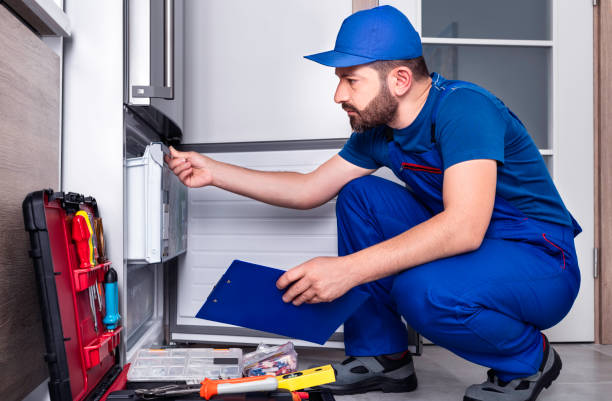 A man in blue overalls holds an oven, demonstrating electric appliance installation.