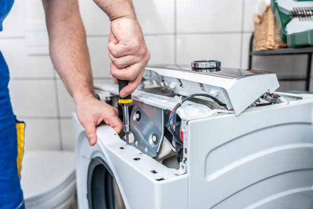 A man wearing overalls is fixing a washer , showcasing his expertise in appliance installation.