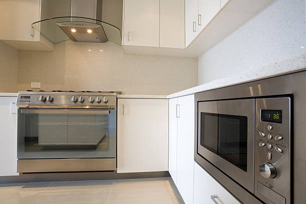 A man and woman stand together in front of an oven, with an over-the-range microwave installed above it.