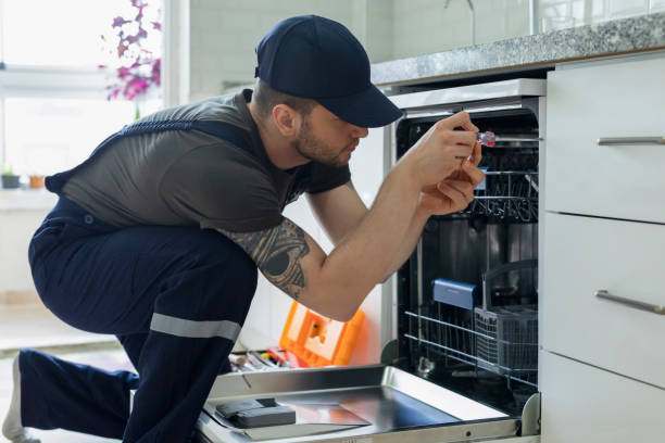 A man repairs an oven in a kitchen, focusing on appliance installation and maintenance tasks.