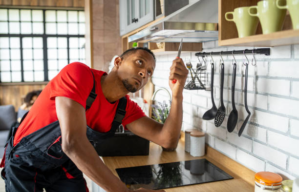  A man in an apron repairs a stove, showcasing cooktop installation services in a home setting.