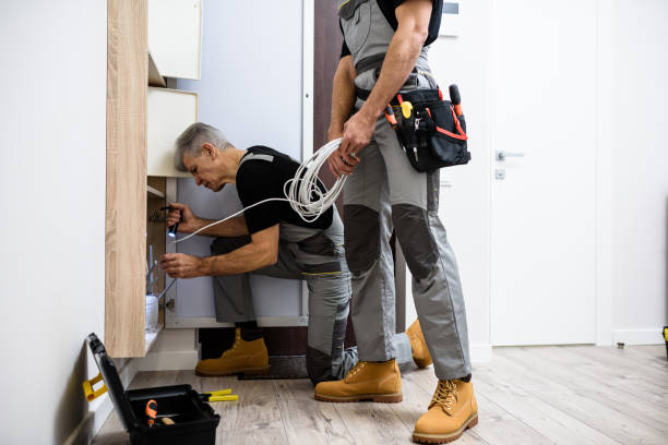 Two men in overalls working together to install a washing machine in a residential area.