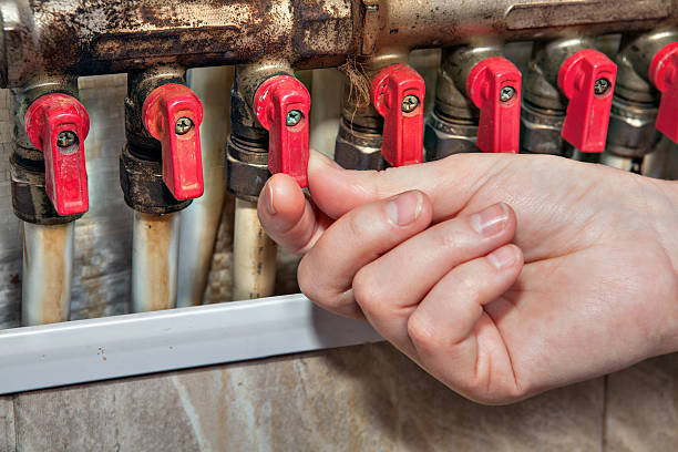 A hand grips a valve on a water heater, highlighting the quality of premium kitchen appliances in the background.